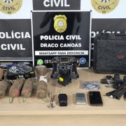 Materiais apreendidos dispostos em uma mesa de fronte a banner da Polícia Civil do Rio Grande do Sul
